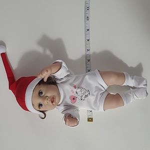 Doll Realistic looking with Santa  hat and white outfit. And blue eyes.